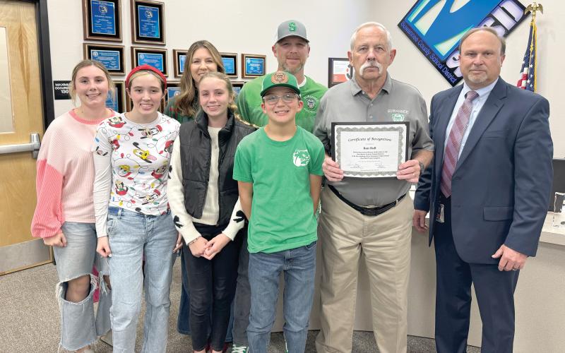 Former Suwannee High track coach Ron Hall was recognized by the Suwannee County School Board at its Tuesday meeting. The district is naming the renovated SHS track complex after Hall, who coached there for 20 years and won the school’s only state track title. Joining Hall are grandchildren McKenna Burnett (front row, from left), Kynzie Hall, Claire Burnett and Kooper Hall; children Casi Burnett (back row, from left) and Kyler Hall and Superintendent Ronnie Gray. (COURTESY)