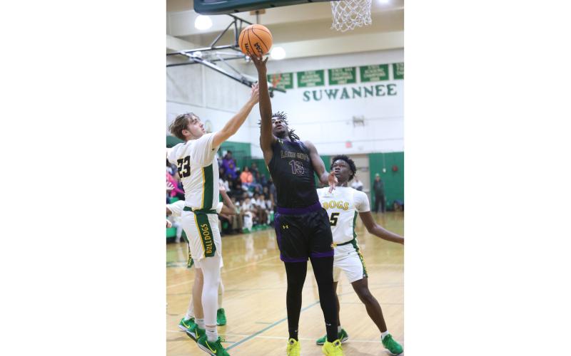 Columbia forward Zavian Douglas slips past Suwannee forward Bryson Parlato (23) and guard MJ Rossin (5) for a layup on Friday night. (PAUL BUCHANAN/Lake City Reporter)
