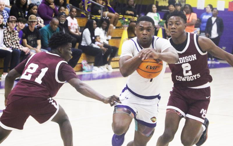 Columbia guard Zamarion Jones drive to the basket between Madison County’s Sean Williams (21) and Jhy Smith (2) on Friday night. (MORGAN MCMULLEN/Lake City Reporter)