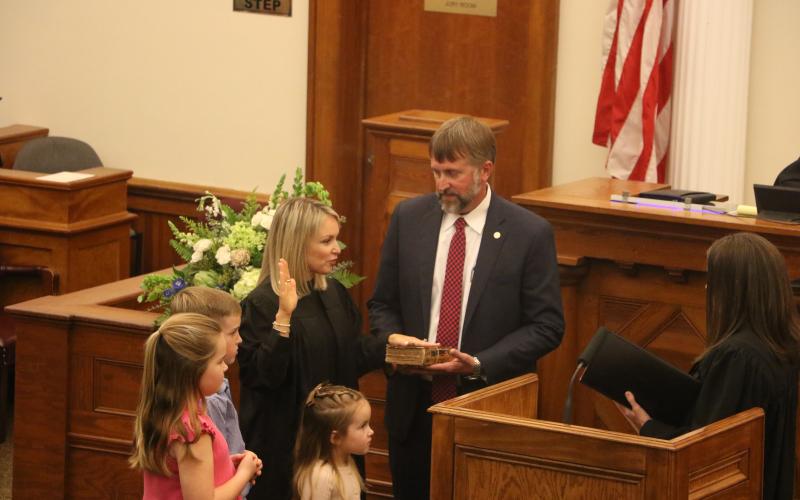 Kathryn ‘Katy’ Land is sworn in as a Third Judicial Circuit judge Friday by Judge Melissa Olin as her husband, Travis, holds the Bible. They are joined by their children Jack, Dylan and Tyler. (MORGAN MCMULLEN/Lake City Reporter)