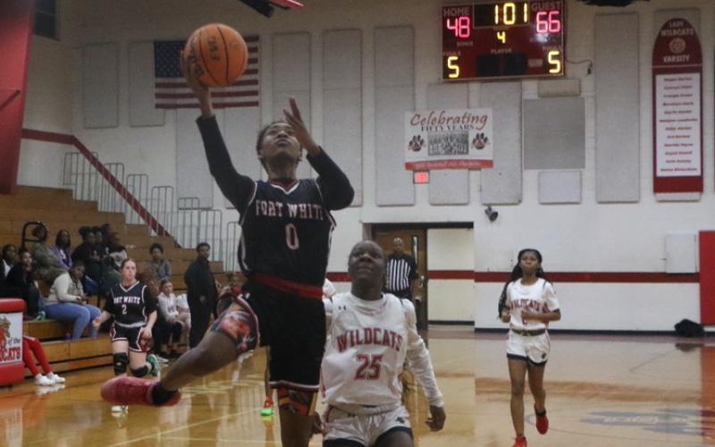 Fort White guard Isreal Hart goes for a layup past Baker County’s Kaitlyn Holland late in the fourth quarter of Tuesday’s win. (MORGAN MCMULLEN/Lake City Reporter)