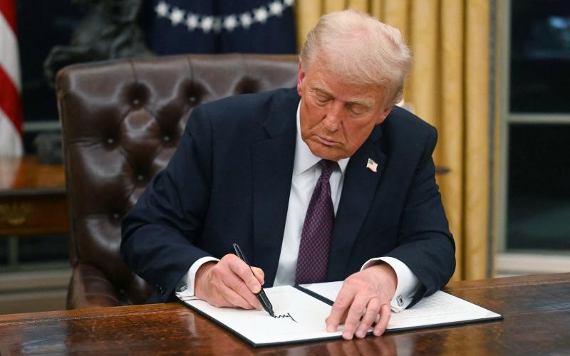 President Donald Trump signs an executive order in the Oval Office at the White House on Monday. One of the executive orders Trump signed either commuted the sentences or pardoned those involved with the Jan. 6, 2021, events at the Capitol. (JIM WATSON/AFP/Getty Images/TNS)