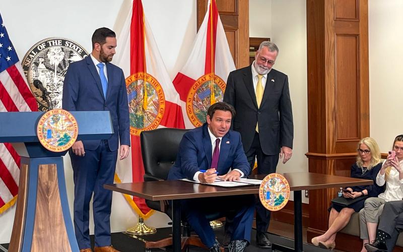 Florida House Speaker Daniel Perez and Senate President Ben Albritton watch Gov. Ron DeSantis sign legislation to address illegal immigration on Thursday. (LAWRENCE MOWER/Miami Herald/TNS)