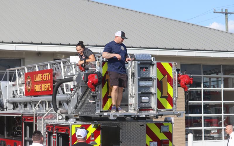 Lake City firefighter Christina Munro (left) flashes a big grin as she and Dustin Alford look over the fire department’s newest engine on Thursday. (TONY BRITT/Lake City Reporter)