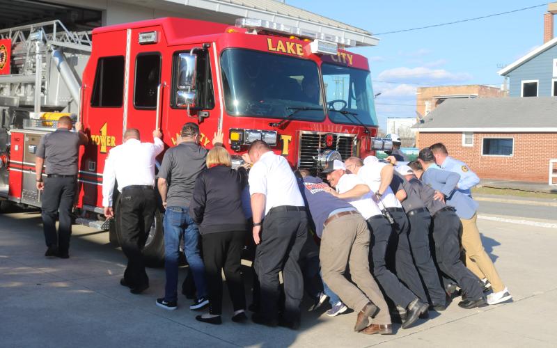 Members of the Lake City Fire Department push the department’s new tower truck into the Lake City Public Safety Building on Tuesday. The push-in ceremony is a traditional way to put new vehicles into service. (TONY BRITT/Lake City Reporter)