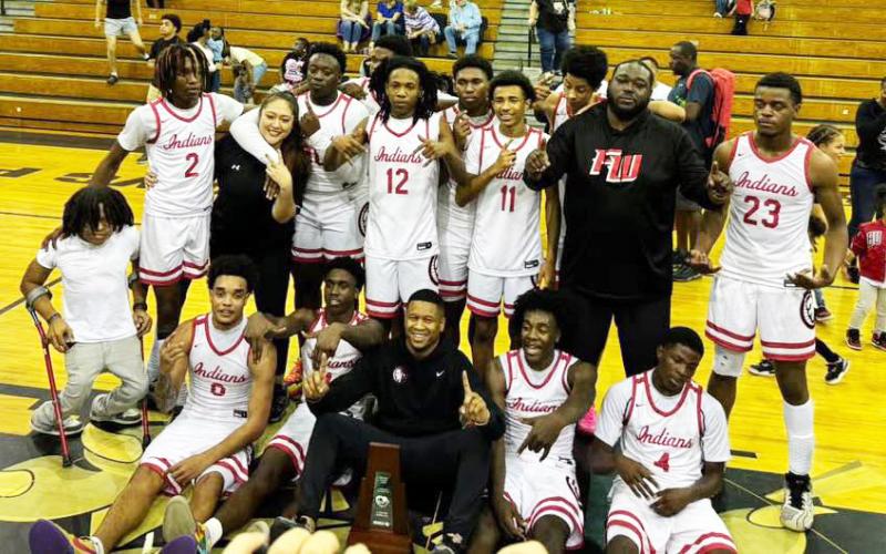 The Fort White boys basketball team celebrates with the District 6-R trophy after defeating Trenton 45-44 on Friday night. (COURTESY)