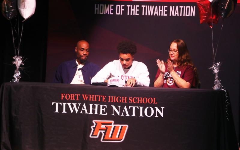 Fort White receiver Tafari Moe (center) signs his letter of intent to play football at Harvard University on Wednesday morning flanked by his parents, Russel (left) and Loretta (right). (MORGAN MCMULLEN/Lake City Reporter)