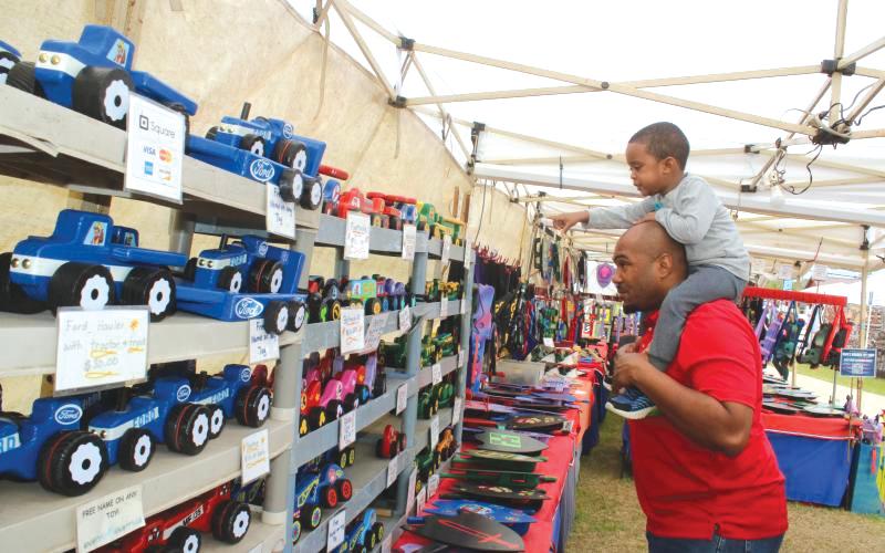 Keaven Jones gives Kaden Jones a ride on his shoulders as the youngster points out wooden cars in a vendor’s booth at last year’s Olustee Festival. (FILE)