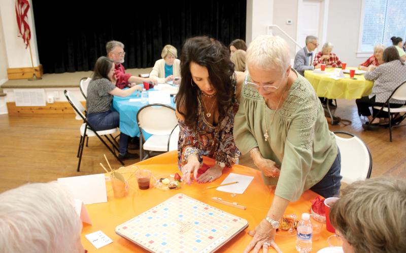 Patti Kahlich (left) and her Scrabble partner Rene Keith, stand up to get a better vantage point while competing in last year’s Scrabble Tournament at the Club House on Lake Isabella. (FILE)