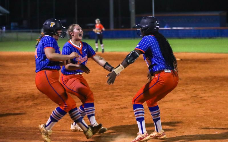 Branford first baseman Victoria Swain (left) and outfielder Ellie Frierson (middle) embrace pitcher Mallory Blue after Blue's walk-off infield single lifted the Buccaneers to a 6-5 win over Trenton on Tuesday. (BRENT KUYKENDALL/Lake City Reporter)