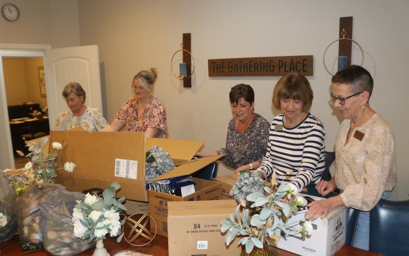 Donna Sandage (from left), Malynn Livingston, Vicki Morrell, Charlene Brown and Lori North open boxes of decorations that will be used for the Pregnancy Care Center’s 40th anniversary banquet, which will take place in a few weeks. (TONY BRITT/Lake City Reporter)