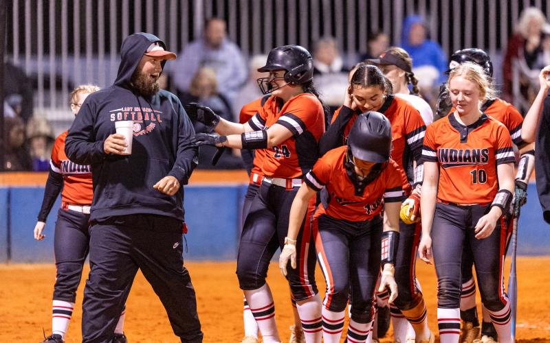 Fort White pitcher Kadence Compton celebrates with teammates and assistant coach Josh Robinson after hitting a home run against Branford on March 10. (JACK HOWDESHELL/Lake City Reporter)