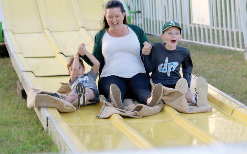 A woman and a pair of children enjoy their trip down a slide at a previous year’s Suwannee County Fair, which opens Friday and runs for nine days. (FILE)