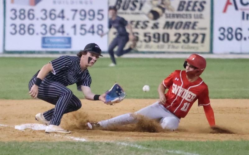 Bishop Snyder center fielder Tristan Silver slides to third base as Suwannee third baseman Jace Moran eyes a throw on Wednesday night. (PAUL BUCHANAN/Lake City Reporter)