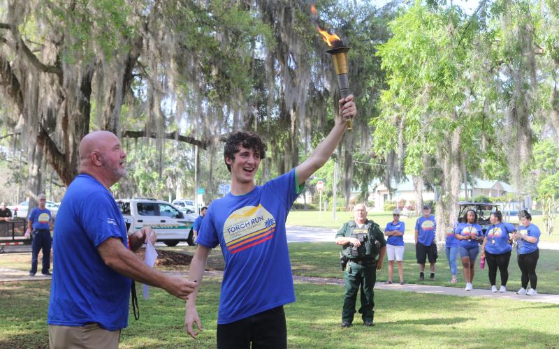 Columbia County Sheriff’s Office Sgt. Clint Dicks (left) looks on as Wyatt Kelly, of Lake City Christian Academy, proudly displays the torch moments before the annual Law Enforcement Torch Run for Special Olympics Florida on Tuesday morning. (TONY BRITT/Lake City Reporter)