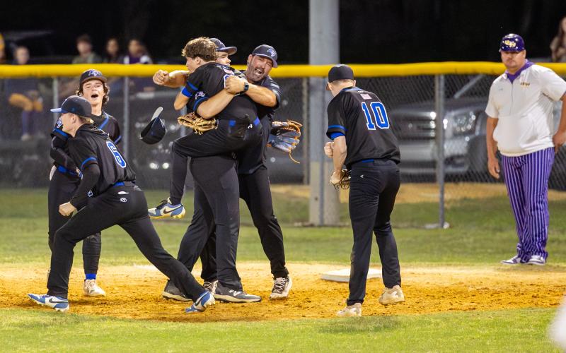 Branford players celebrates with coach Brian Tomlinson after defeating Union County 4-2 in the District 6-R semifinals Tuesday night. (JACK HOWDESHELL/Lake City Reporter)