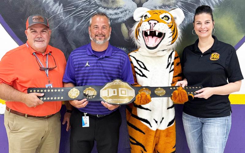 Columbia High Principal Trey Hosford (second from left), the school’s mascot and Student Government Director Tia Gainey accept the Florida Department of Transportation District 2 Battle of the Belts championship belt. (COURTESY)