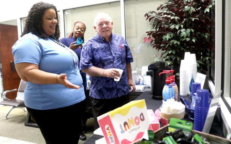 Chanel Neff (clockwise from left), a City of Lake City Customer Service Department employee, encourages Tequela Donaldson and Carroll Lee to get some donuts and coffee during the city’s customer service appreciation festivities last Friday. (TONY BRITT/Lake City Reporter)