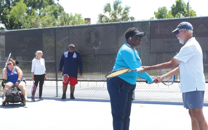 Stacy McCabe gets instructions on her backhand grip from Coach Mark Mansbach, as he teachers McCabe and other veterans the game of tennis through a local program. (TONY BRITT/Lake City Reporter)
