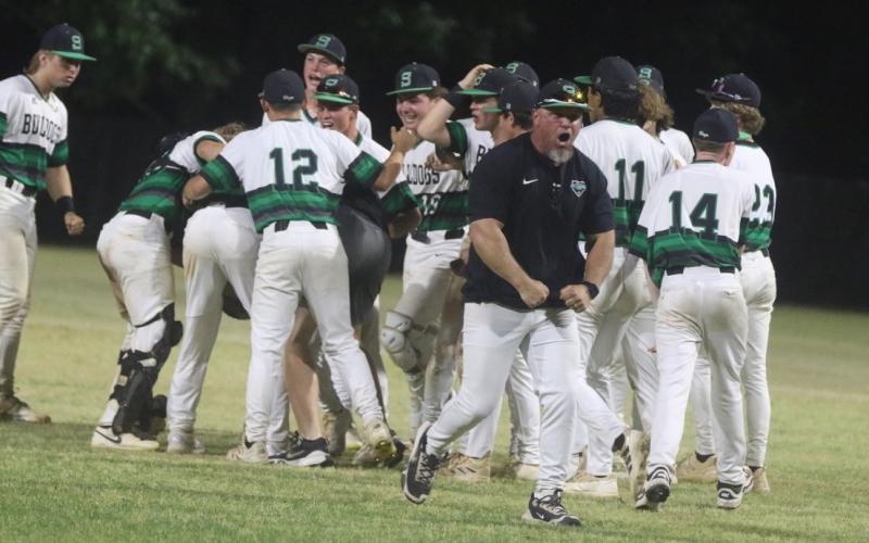 The Suwannee baseball team celebrates with coach Billy Moran out front after the Bulldogs’ 6-5 win over Baldwin in a decisive Game 3 of the Region 1-3A quarterfinals. (MORGAN MCMULLEN/Lake City Reporter)