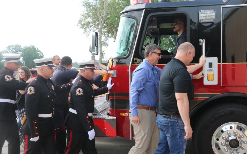 Suwannee County Fire Rescue firefighters and county officials take part in the traditional push-in ceremony Thursday to officially welcome Engine 11 into service for the county’s fire service. (JAMIE WACHTER/Lake City Reporter)