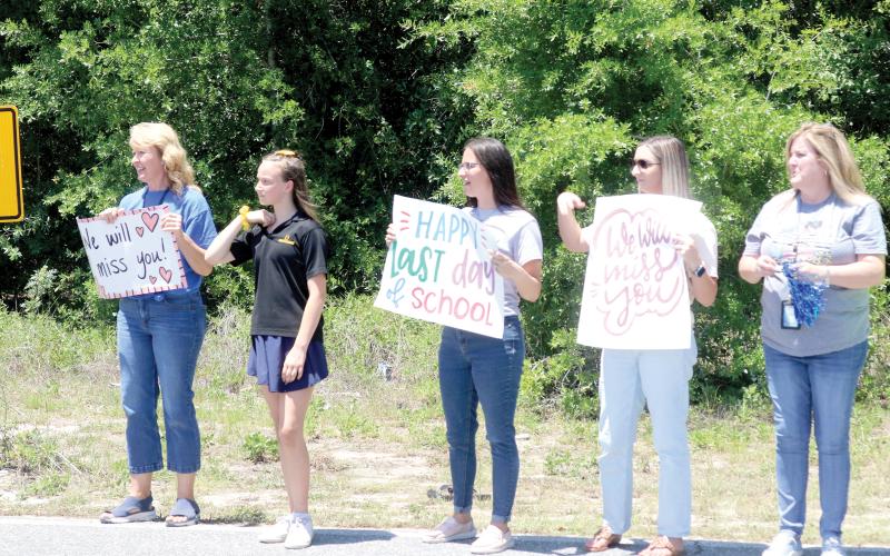 Eastside Elementary School faculty and staff members stand along SE Beech Street on Friday afternoon with signs, as students head home for summer vacation. Eastside Elementary School completed its last day of classes on Friday in the building that was opened in 1959. The building will will be demolished in a few weeks, making way for a new Eastside Elementary School. (TONY BRITT/Lake City Reporter)