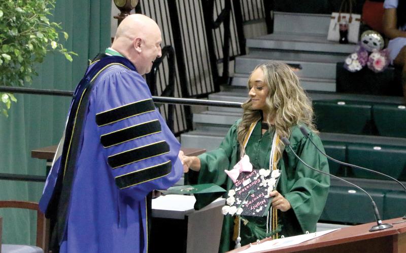 Sakiya Merriex receives her associate in arts degree from Florida Gateway College President Larry Barrett during commencement Thursday at the Howard Center. (MORGAN MCMULLEN/Lake City Reporter)