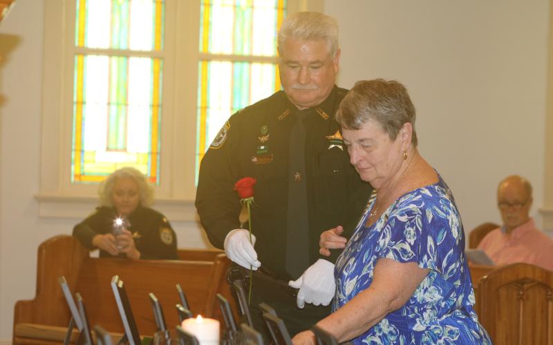 Pat Davis places a rose to honor her son, late Columbia County Sheriff’s Deputy Jeff Davis, during last year’s Public Safety Memorial ceremony. (FILE)