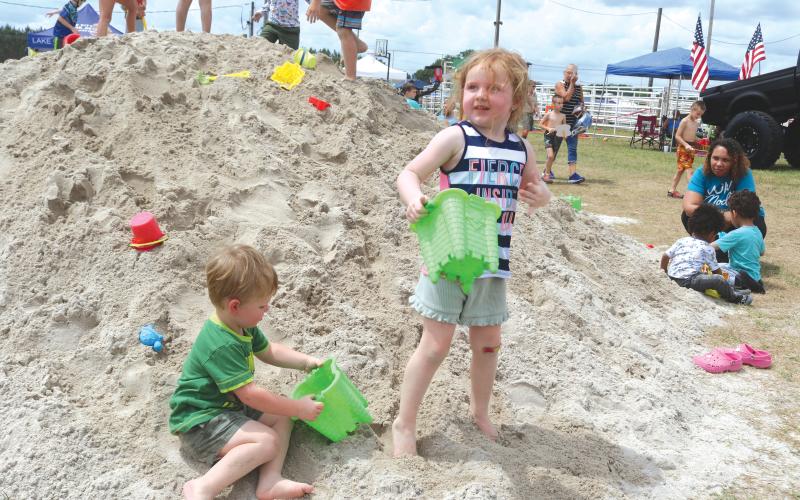 Benton Graham (from left), 2, and Lundee Graham, 4, play in a pile of sand during the 10th Annual Kiwanis Kids Day which took place Saturday attracting hundreds of children. (TONY BRITT/Lake City Reporter)