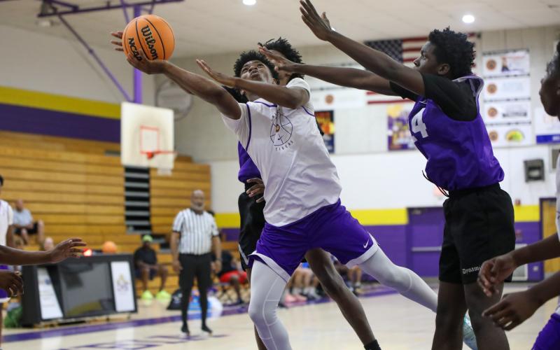 Columbia’s Murkail Cray splits a pair of Gainesville defenders on a layup attempt Thursday night during a summer league game. (BRENT KUYKENDALL/Lake City Reporter)