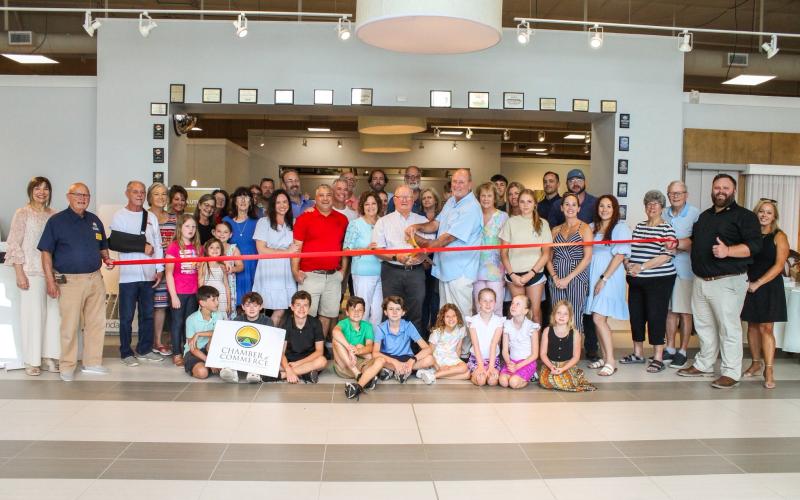 Marc and Paul Vann, co-owners, cut the ceremonial ribbon to celebrate the grand re-opening of Vann Carpet One Floor and Home on Thursday. The Vann’s are joined by family, friends, employees, Lake City and Lake City-Columbia County Chamber of Commerce officials. (COURTESY LAKE CITY-COLUMBIA COUNTY CHAMBER OF COMMERCE)