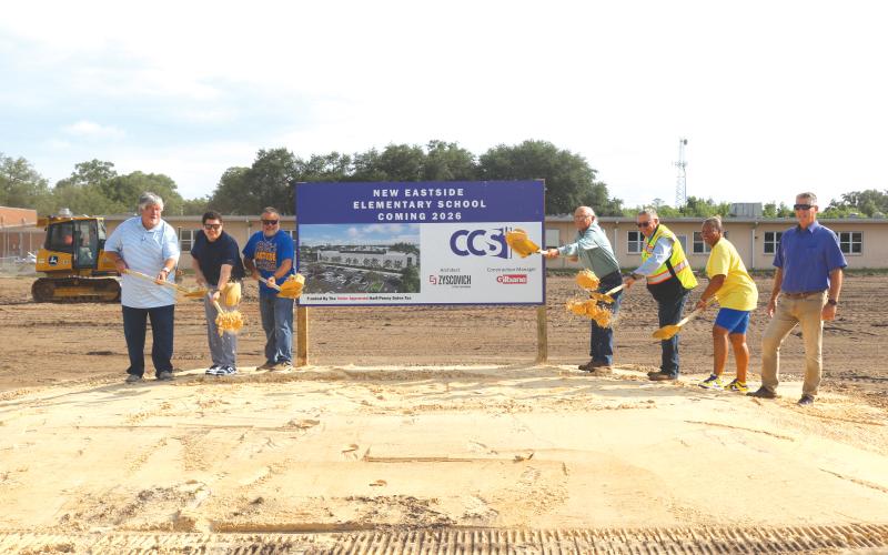 Keith Couey (from left), Hunter Peeler, Roger Little, Keith Hudson, Fred Gaylard, Scharlotte Stewart and Todd Widergren toss soil to commemorate the official beginning of construction of the new Eastside Elementary School. The groundbreaking ceremony took place on Wednesday morning amid construction crews beginning the first stages of demolition work at the school. (TONY BRITT/Lake City Reporter)