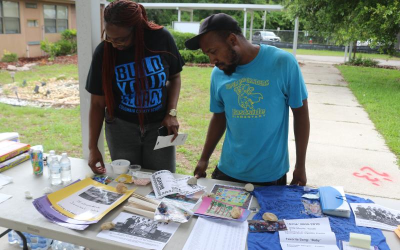Shanetha Anthony (from left) and Damarrick Hendon, look through Eastside Elementary School items that were pulled from a time capsule to the school’s final walkthrough on Thursday afternoon. (TONY BRITT/Lake City Reporter)