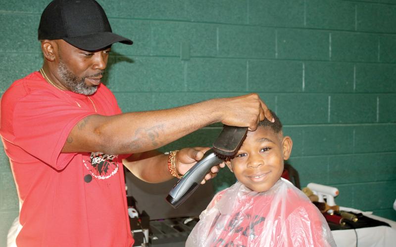 Tyrone Mullins, giving a haircut at a previous Community Barbers Back to School Bash, said this is a special year for the event as it marks its 10th anniversary. (FILE)