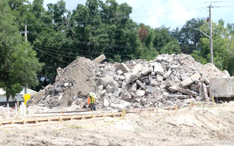 A construction worker looks at some concrete slabs that have been poured on the Eastside Elementary School campus Wednesday as a mountain of debris from the previous school is piled up behind him. (TONY BRITT/Lake City Reporter)