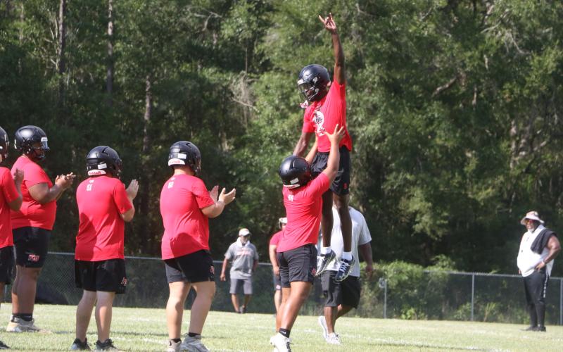 Fort White quarterback Jayden Jackson is hoisted to the air by left tackle Tayvin Fleming ahead of Monday’s practice. (MORGAN MCMULLEN/Lake City Reporter)