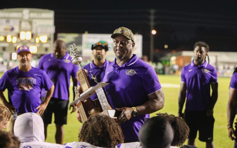 Columbia coach Brian Allen holds the Old Oaken Bucket trophy after the Tigers’ 42-6 rout of Suwannee at Langford Stadium on Friday night. (BRENT KUYKENDALL/Lake City Reporter)