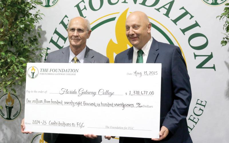 Van Long (left), the Foundation For Florida Gateway College board chair, stands with Lawrence Barrett, Florida Gateway College President, holding a ceremonial check for $1.3 million, representing funds for scholarships and to support other programs at the college. (TONY BRITT/Lake City Reporter)