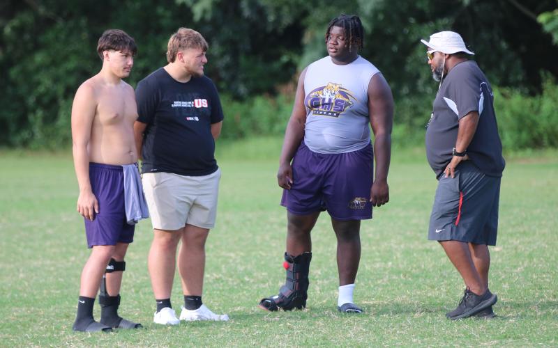 Columbia offensive lineman De’manuel Jones (right center) talks to offensive linemen Aiden Jenkins (left) and Zackery Grimes (left center) as well as running backs coach Quintin Callum during Monday’s practice. (JORDAN KROEGER/Lake City Reporter)
