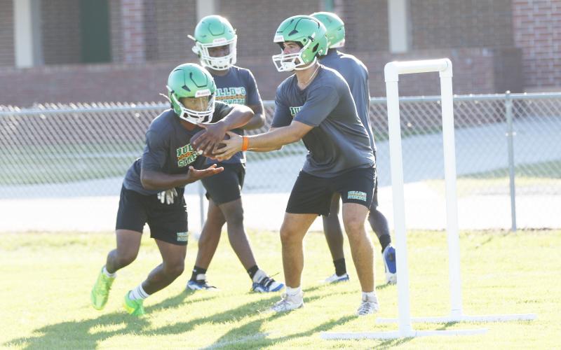 Suwannee quarterback Thomas Sikes (right) hands the ball off to running back Lou Jack Smith during Monday’s practice. (JAMIE WACHTER/Lake City Reporter)