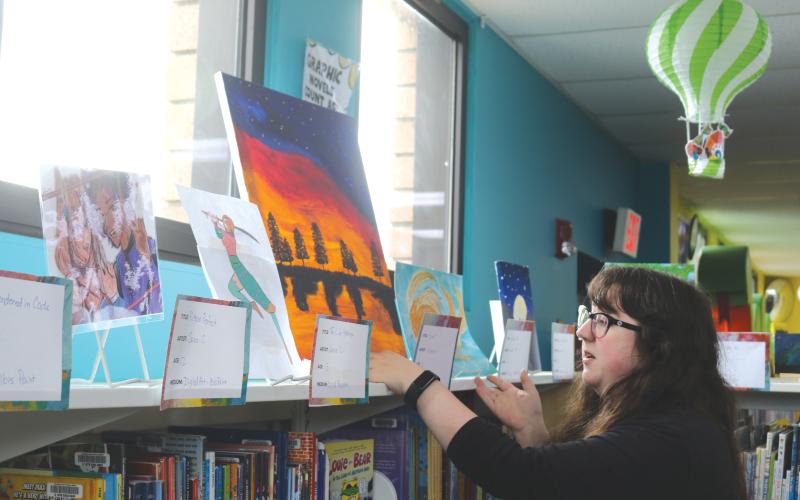 Columbia County Public Library Programming Specialist Emma Chieuw arranges art pieces ahead of the library's 2025 Youth Art Contest. (TONY BRITT/Lake City Reporter)