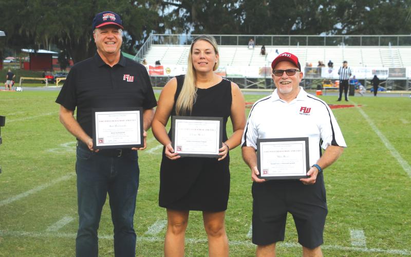 Bob Hochmuth (from left), Tiffany Moses and Mike Rizzi accept their plaques after being inducted in the Fort White Athletics Hall of Fame ahead of Friday’s football game against Belleview. Xavier Blake and Jordan Talley (not pictured) were also inducted Friday but could not attend the ceremony. (MORGAN MCMULLEN/Lake City Reporter)