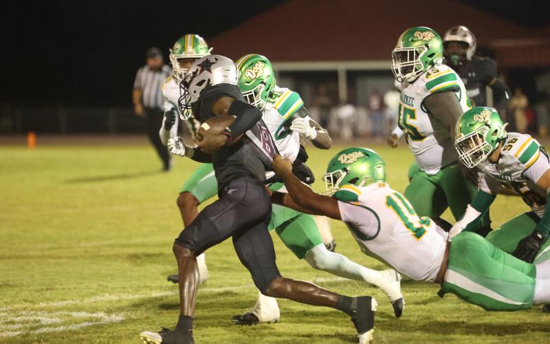 Madison County quarterback LJ Crumity pulls away from Suwannee linebacker Marco Rojas as De’aumann Jones closes in Friday night at Boot Hill. (PAUL BUCHANAN/Lake City Reporter)