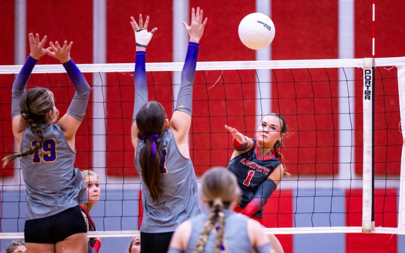 Lafayette hitter Brooke Lamb fires a shot as Columbia hitters Chloe Nickelson (19) and Ava Christie (17) on Monday. (JACK HOWDESHELL/Lake City Reporter)
