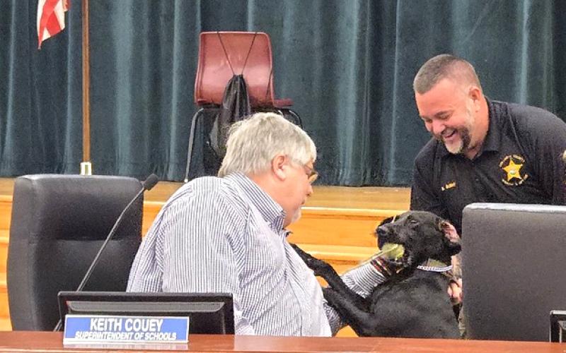 Columbia County Schools Superintendent Keith Couey (left) greets Jade as Columbia County Sheriff’s Deputy Kevin Bailey introduces her to the school board. (COURTESY COLUMBIA COUNTY SHERIFF'S OFFICE)