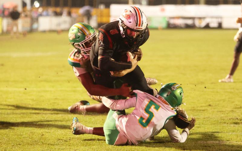 Baker County quarterback Hudson Register runs through Suwannee defenders Marco Rojas (15) and Kamari Lovett for the game-winning score in overtime Friday night. (PAUL BUCHANAN/Lake City Reporter)