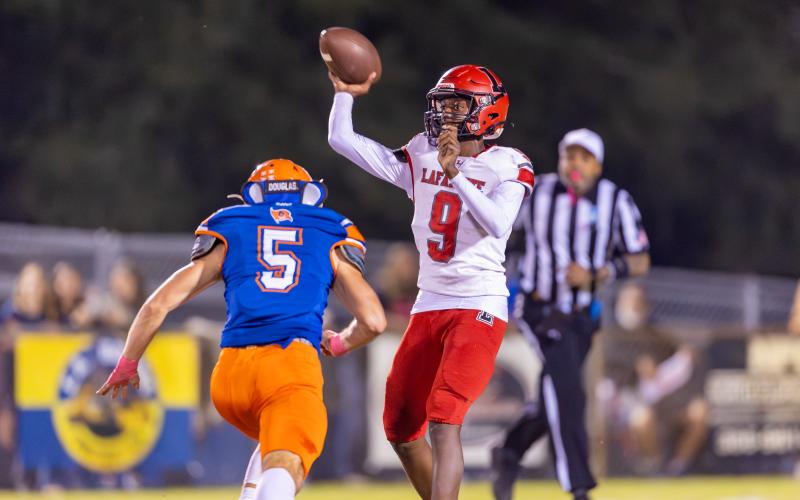 Lafayette quarterback Tywan Williamson releases a pass as Branford’s Devin Waller closes in Friday. (JACK HOWDESHELL/Lake City Reporter)