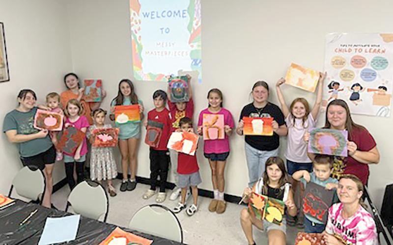Participants in the first ‘Messy Masterpieces’ class at the West Branch Library show off their artwork Saturday. (COURTESY)