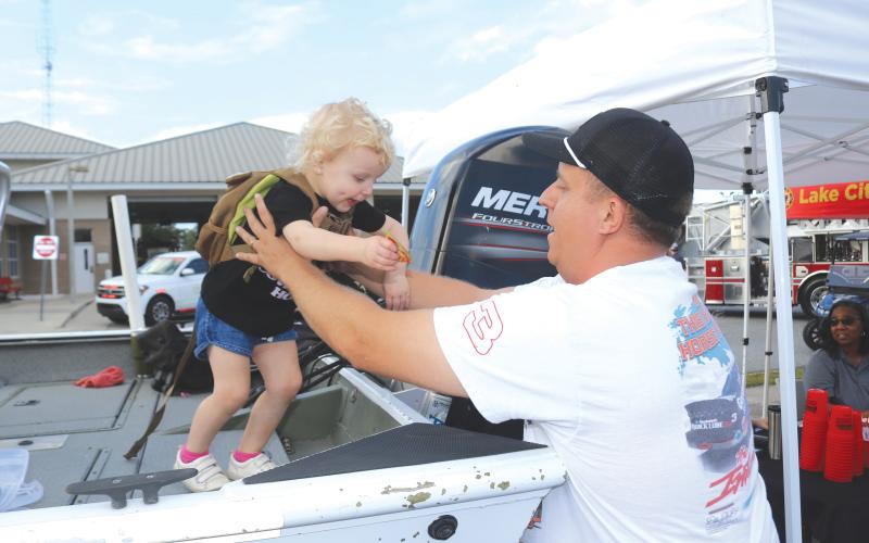 Landry Levai (from left), 2, gets a lift from Blaise Levai after walking on the Columbia County Sheriff’s Office Search and Rescue Boat during the National Night Out event on Tuesday evening. (TONY BRITT/Lake City Reporter)