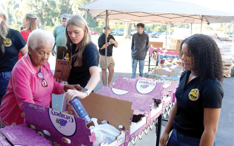 Catholic Charities volunteers Carrie Alexander (clockwise from left), Madeline Moore and Amani Tunsil add items to boxes that were given to local families for the annual Catholic Charities Thanksgiving Basket giveaway, which was held Thursday. (TONY BRITT/Lake City Reporter)